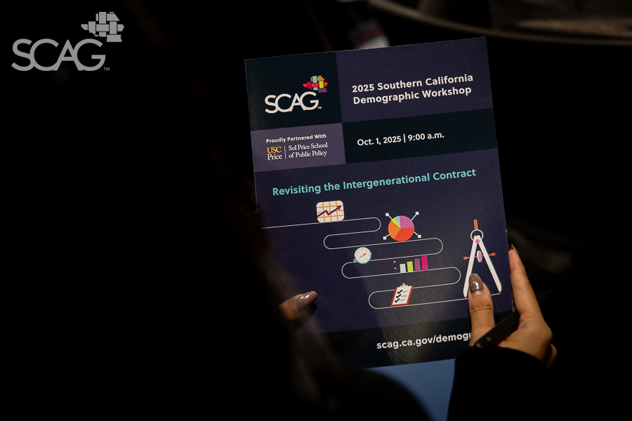 Hands holding a SCAG workshop flyer in a dim setting.