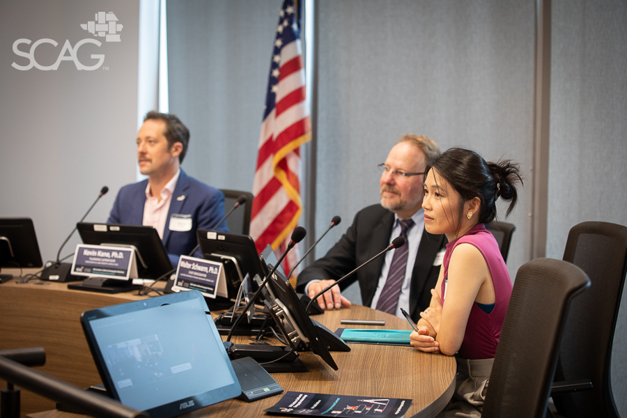 Panelists at a conference table with an American flag in the background.