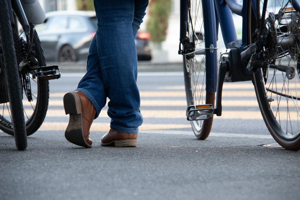 A person in jeans walks between parked bicycles.