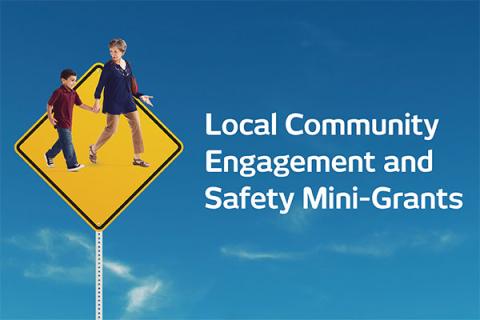 Traffic sign with adults and child walking, blue sky background.