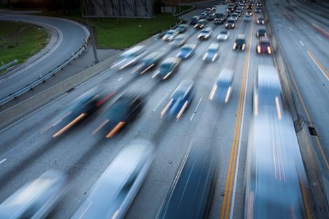 Busy highway with blurred cars in motion, blue tones, evening light.